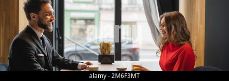 vue latérale d'un couple heureux regardant l'un l'autre près des boissons dans le restaurant, bannière, image de stock Banque D'Images