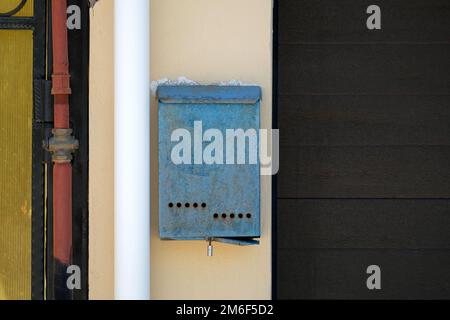 Une ancienne boîte aux lettres est suspendue sur le mur entre le tuyau et le seuil. Personne Banque D'Images