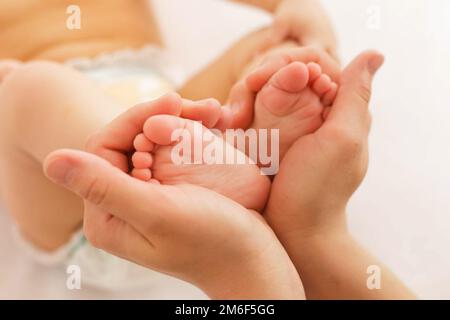 La mère tient les jambes du bébé. Banque D'Images