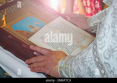 Gros plan du prêtre lisant la sainte bible. Prêtre pendant la cérémonie de baptême. Bible et icône Banque D'Images