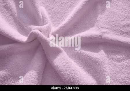 Serviette en tissu éponge molletonné rose, un exemple simple de la texture d'un tissu doux et molletonné, un fond de plis Banque D'Images