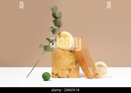 Encore vie composition moderne. Barre de shampooing solide et matériaux naturels un équilibre d'idée. Peigne en bois, éponge Luffa, eucalyptus sur fond beige. Banque D'Images