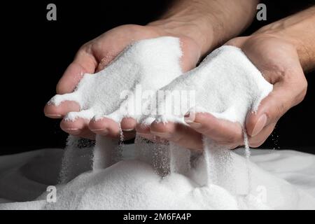 Les mains des hommes gardent le sable dans leurs paumes et répande des grains de sable à travers leurs doigts. Concept du flux de la vie Banque D'Images