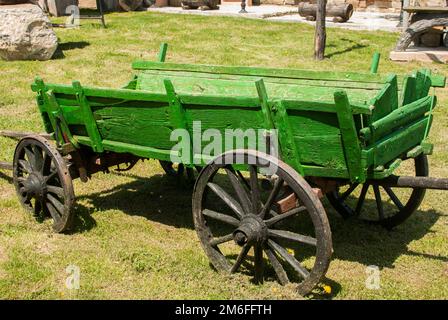 Vieux chariot rural en bois vert à proximité dans le jardin de la maison de village Banque D'Images