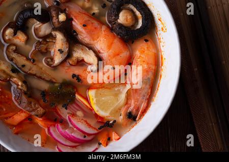 Soupe miso aux moules, crevettes, champignons shiitake et légumes. servi sur une table en bois brun foncé. pose à plat Banque D'Images