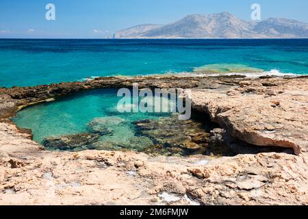 Rocky plage île de Kimolos, île de Keros à l'arrière Banque D'Images