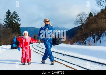 mère et fille portent des combinaisons de ski près du chemin de fer Banque D'Images