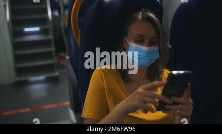 Femme en masque médical voyageant à l'intérieur du train. Banque D'Images