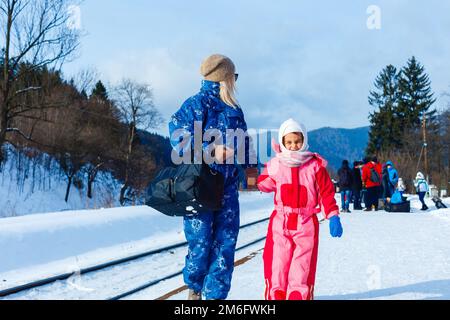 mère et fille portent des combinaisons de ski près du chemin de fer Banque D'Images