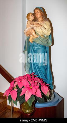 Statue de Marie et du bébé Jésus avec des poinsettias roses pour Noël à Saint Joseph's Catholic Church à Taylors Falls, Minnesota, États-Unis. Banque D'Images