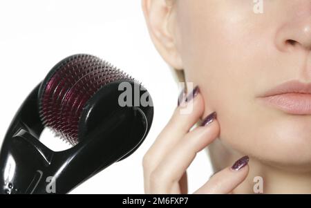 Massage du visage avec dermaroller microneedle pour le traitement des cicatrices, des rides et pour le rajeunissement du visage. Soins de la peau simples et bon marché à la maison. Banque D'Images