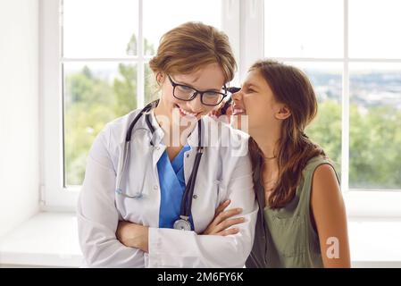 Adolescente drôle ayant l'amusement regardant par otoscope à l'oreille d'une femme sympathique médecin. Banque D'Images