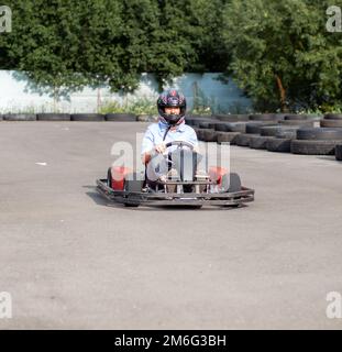 Une fille ou une femme dans un casque roule un kart sur une piste spéciale. Banque D'Images