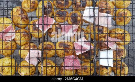 Pommes de terre grillées au bacon, cuites au barbecue. Mise au point sélective. Petites pommes de terre entières avec morceaux de bacon et grille Banque D'Images