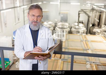 Un technologue sérieux en brasserie prend des notes dans son journal Banque D'Images