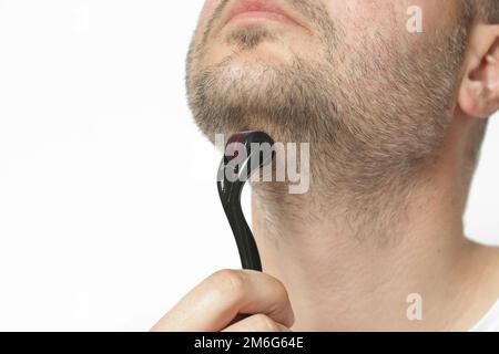 Massage du visage avec dermaroller microneedle pour le traitement des cicatrices, des rides et pour la croissance de la barbe. Soins de la peau simples et bon marché à la maison. Banque D'Images