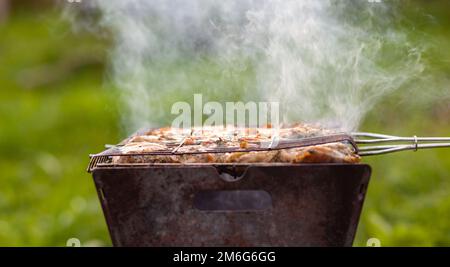 Morceaux de viande accrochés sur des brochettes de métal sur le gril au coucher du soleil Banque D'Images