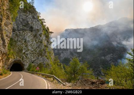 Route et tunnel au lac Piva dans le parc national Dormitor du Monténégro pendant un feu de forêt à la fin de l'été Banque D'Images