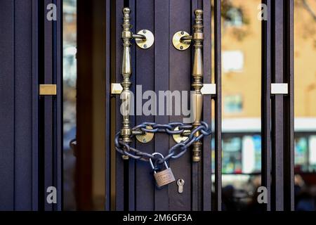 Cadenas. Chaîne. Cadenas sur un portail d'un bâtiment pour que les voisins ne puissent pas y accéder. Affecté par la ligne 7B du métro San Fernando de Henares Banque D'Images