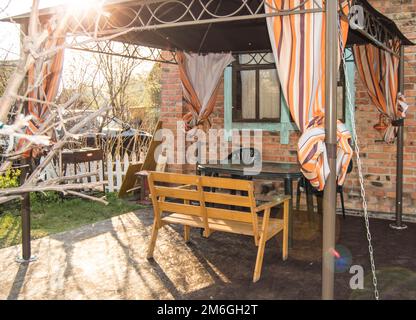 Une belle aire de loisirs pour une famille dans une maison de campagne, une tente avec un banc et une table sur le fond d'une maison en briques Banque D'Images