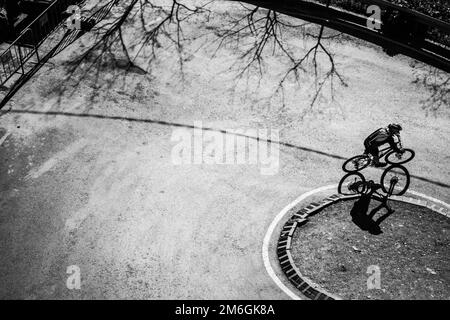 Un motard qui descend Tibidabo à Barcelone par une belle journée d'hiver. Photo en noir et blanc avec beaucoup d'ombres dures. Banque D'Images