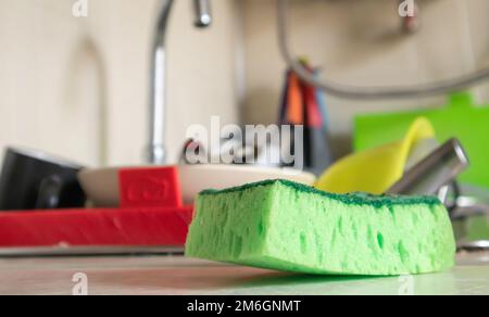 Distributeur d'éponge verte et de savon liquide pour laver la vaisselle sur un évier sale complètement avec la vaisselle et les ustensiles de cuisine. Lavage d Banque D'Images