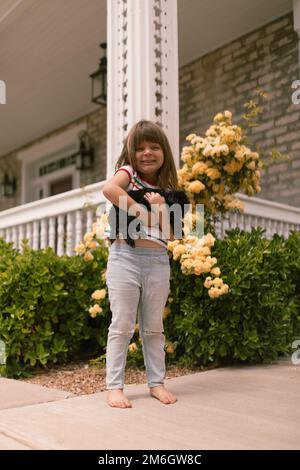 Petite fille tenant le chiot noir shih tzu devant le spri jaune Banque D'Images