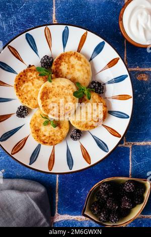 crêpes au fromage cottage sur une assiette, mûres, crème aigre. br Banque D'Images