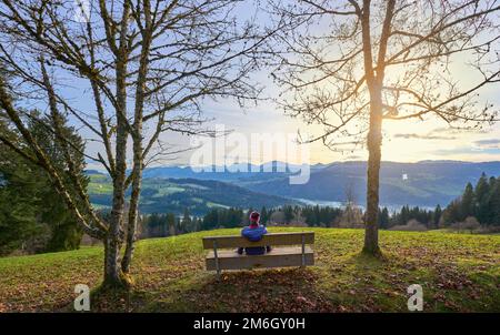 Femme se reposant à un point de vue au lever du soleil dans les montagnes d'Allgaeu, près d'Oberstaufen, Bavière, Allemagne Banque D'Images