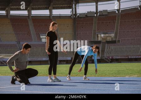 Un homme et deux femmes sont sur le point de s'entraîner au cardio. Ils feront du jogging au stade Banque D'Images