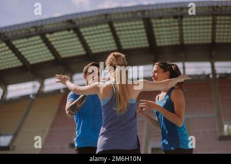 Une heureuse fille blonde est sur le point de féliciter ses amis masculins et féminins pour leur succès. Elle leur donne un câlin Banque D'Images