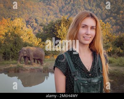 Femme souriante aux cheveux longs devant les éléphants à pied dans le parc safari Banque D'Images