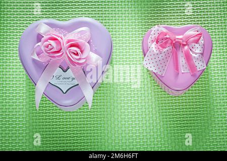 Boîtes cadeau en forme de coeur rose en métal sur fond vert concept de célébrations. Banque D'Images