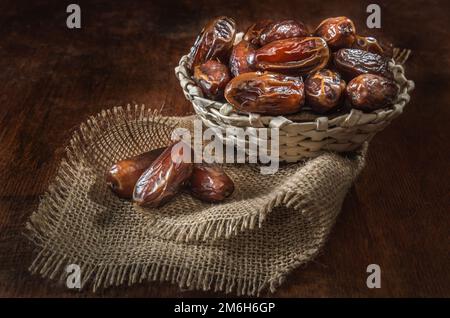 Dates mûres dans un panier sur fond de bois sombre Banque D'Images