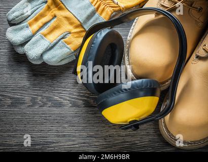 Gants de sécurité bottes de travail étanches casque antibruit sur panneau en bois. Banque D'Images