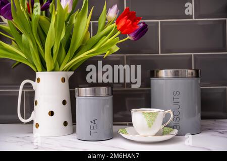 thé et biscuits encore vivants le matin avec tulipes fraîches dans une verseuse blanche sur un plateau de cuisine en marbre Banque D'Images