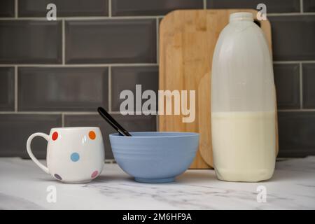 lait de petit déjeuner végétalien amandes, soja, lait d'avoine substituts au lait de vache sur céréales de petit déjeuner et une tasse de thé sur le plan de travail en marbre dans la cuisine Banque D'Images