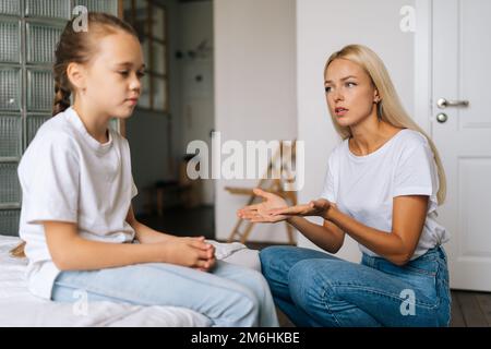 Une jeune mère irritée donne des leçons à une petite fille têtue pour son mauvais comportement à l'école ou à la maison. Concept de problèmes familiaux, conflit, crise. Banque D'Images