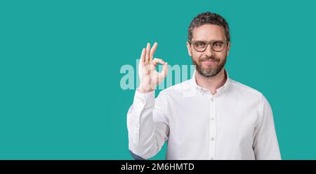 homme regarder dans les lunettes montrer ok isolé sur fond bleu. look homme mûr Banque D'Images