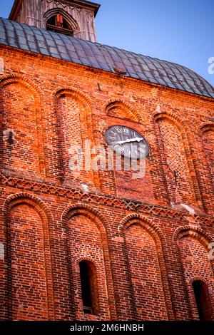 Une tour d'horloge orne un grand bâtiment de brique d'église. Banque D'Images