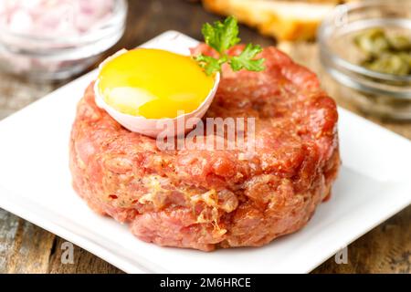 Tartre au steak avec œuf ouvert sur bois Banque D'Images