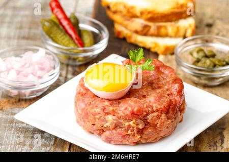 Tartre au steak avec œuf ouvert sur bois Banque D'Images