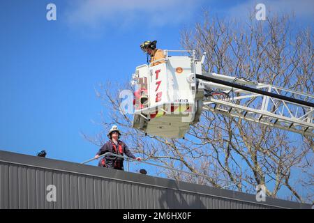 Les membres de la base navale des services de sécurité et d'incendie et d'urgence de Newport répondent à un appel de plusieurs personnes bloquées sur le toit d'un bâtiment pendant l'exercice Citadel Gale 2022 à l'installation. Dans ce scénario, le bâtiment est inondé d’eau et l’eau stagnante nécessite l’utilisation de la tour 72 pour pouvoir atteindre le groupe et les extraire du toit du bâtiment. Il s’agissait de l’un des trois exercices de formation axés sur le feu qui ont été inclus dans les injections de forage de l’installation dans le cadre de l’exercice annuel sur les ouragans. Banque D'Images