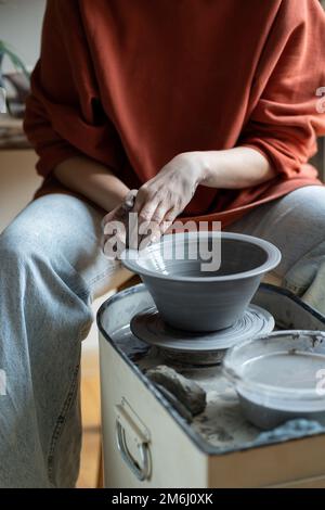 Maître en céramique créant du grès fait à la main sur la roue en studio, formant de l'argile en forme Banque D'Images