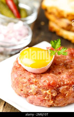 Tartre au steak avec œuf ouvert sur bois Banque D'Images