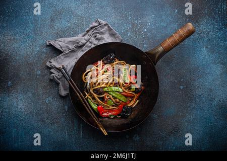 Faites sauter les nouilles asiatiques avec les légumes dans un wok noir Banque D'Images