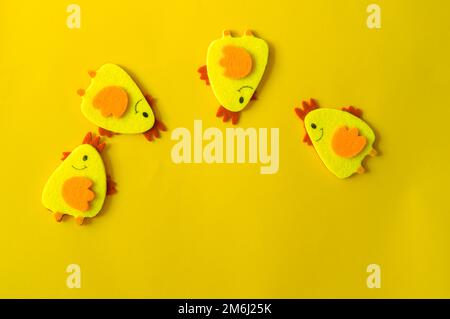 Quatre poulets décoratifs en feutre jaune disposés en demi-cercle sur fond jaune. Concept minimaliste, carte de Pâques mignonne avec un c Banque D'Images