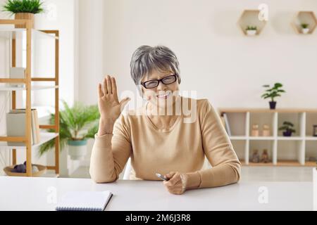 Bonne femme âgée souriant et saluant lors d'un appel vidéo ou d'une conférence en ligne Banque D'Images
