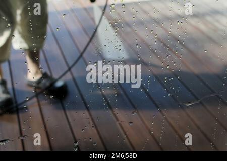 Nettoyage de surface sous tension. Homme nettoyant terrasse avec un lave-linge. Nettoyeur haute pression d'eau sur la surface de terrasse en bois. Banque D'Images