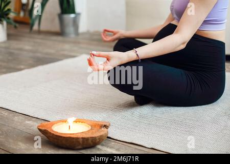 Femme enceinte courte assise en position yoga dans la salle de spa, se concentrer sur la bougie de coco, se détendre et méditer Banque D'Images